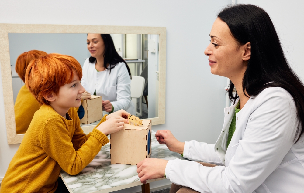 Female,psychologist,working,with,boy,patient,in,office,while,play